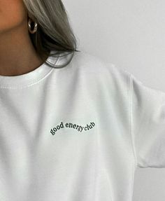 a woman wearing a white t - shirt with the words good energy club on it