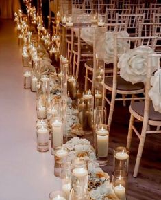 rows of candles are lined up on the floor in front of white flowers and chairs