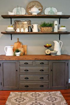 an old dresser is painted gray and has shelves with dishes on it, along with other items