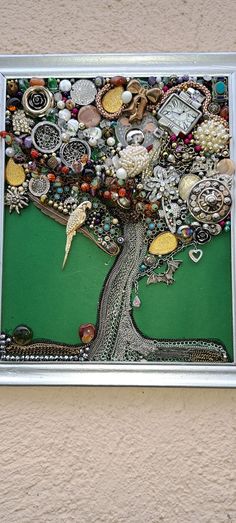 a tree made out of buttons and other items on a wall with a silver frame