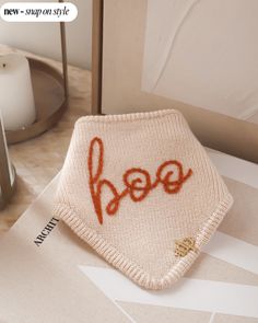 a knitted item with the word hope written in orange on it sitting on a table next to a candle