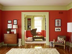 a living room with red walls and white carpet on the wooden floored flooring