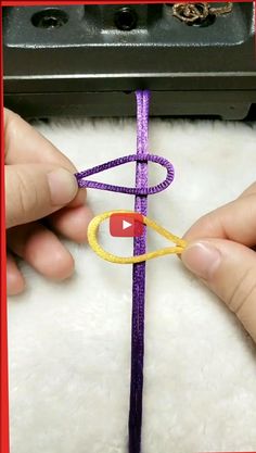 someone crocheting the end of a purple string with a yellow circle on it