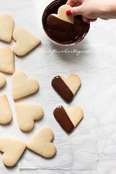 someone is decorating heart shaped cookies with chocolate