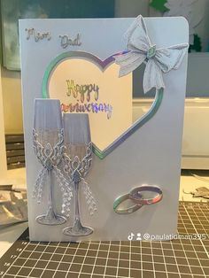 a happy birthday card with two wine glasses and a bow on the front, sitting on a table