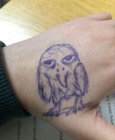 an owl tattoo on someone's wrist is shown in purple ink, which appears to be blue