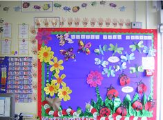 a bulletin board with flowers and bugs on it in front of a classroom wall decorated with magnets