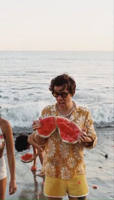 two women standing on the beach with watermelon slices