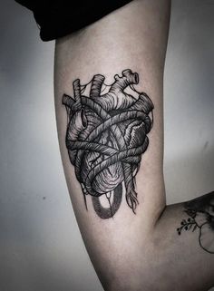 a black and white photo of a human heart tattoo on the right arm, with an arrow in it