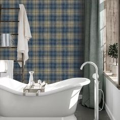 an old fashioned bathtub in a bathroom with blue and yellow plaid wallpaper on the walls