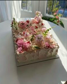 a white box with pink and red flowers on it sitting on a table next to a window