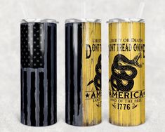 two black and yellow soda cans with straws in them, both decorated with an american flag