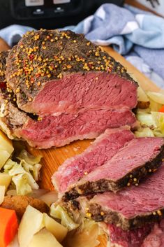 a roast beef sandwich on a cutting board with potatoes and carrots