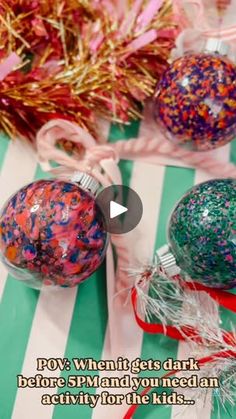 two christmas ornaments sitting on top of a green and white striped table cloth next to candy