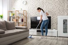 a woman cleaning the floor with a mop in front of a tv and couch