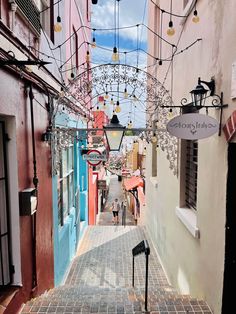 an alleyway with many lights and signs hanging from the ceiling, in between two buildings