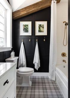 a white toilet sitting next to a bath tub in a bathroom under a wooden beam