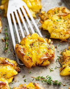 a fork with some food on it next to some potatoes and other things in the background