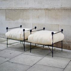 two white chairs sitting next to each other on top of a cement floor near a wall