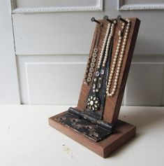 a wooden stand holding several necklaces on top of a white table next to a door