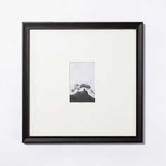 a black and white photo hanging on the wall next to a framed photograph with mountains in the background