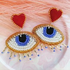 two pairs of blue and white beaded eye earrings with red hearts on top of them