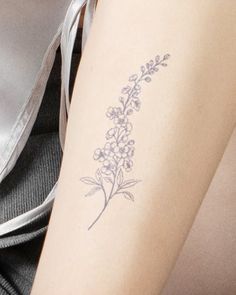 a woman's arm with a tattoo on it that has flowers and leaves drawn on it