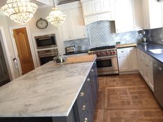 a large kitchen with marble counter tops and stainless steel appliances