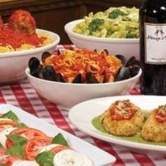 a table topped with plates of food next to bottles of wine and glasses of wine