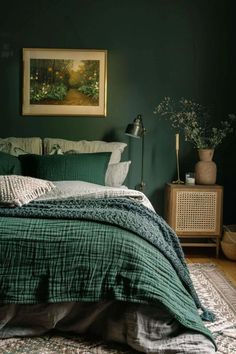 a bed with green sheets and pillows in a dark colored room next to a painting on the wall