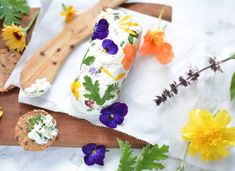 an assortment of food on a cutting board next to flowers