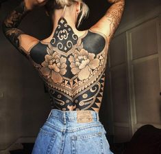 the back of a woman's body with tattoos on her upper and lower half