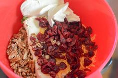 a red bowl filled with nuts, yogurt and raisins on top