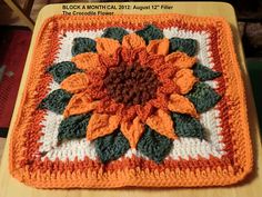 an orange and white crocheted square with a flower on it's center