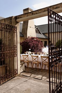 an outdoor dining area with table and chairs set up for dinner outside the gated entrance