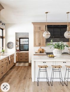 a large kitchen with wooden cabinets and white counter tops, two stools at the island