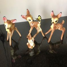 three little deer figurines sitting on top of a black table next to a butterfly