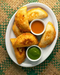 three pastries on a plate with dipping sauces