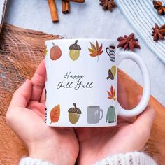 a person holding a coffee mug with autumn leaves on it