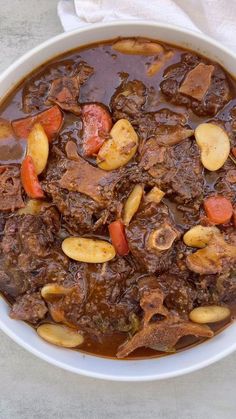 a white bowl filled with beef and potatoes