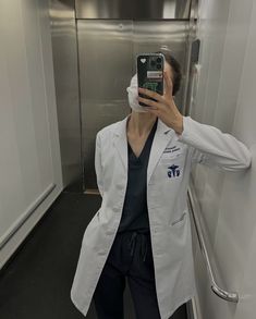 a woman taking a selfie in a white lab coat