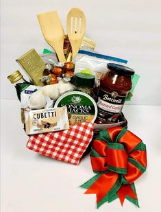 an assortment of food and condiments in a basket with a red bow on the side