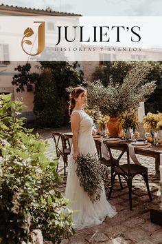 a woman in a wedding dress standing next to a table with flowers and greenery