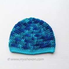 a crocheted blue and green hat sitting on top of a white table