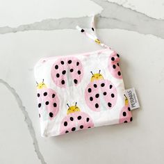 a pink and black ladybug print pouch on a white surface with a tag