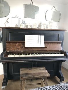 an old piano in a room with mirrors on the wall and a small stool next to it