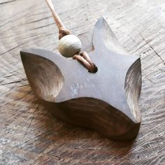 a wooden object with two balls hanging from it's end on a string that is attached to a piece of wood