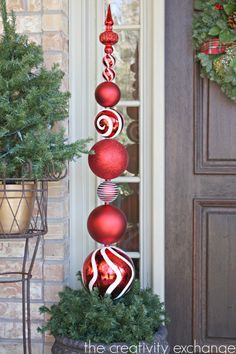 red ornaments are hanging on the side of a door and in front of a potted planter