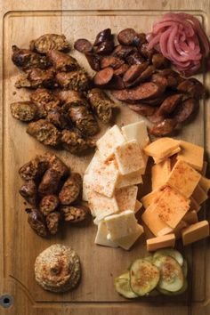 a wooden cutting board topped with meat and cheese