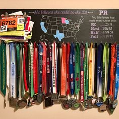 a bunch of medals are hanging on the wall next to a chalkboard that says marathon